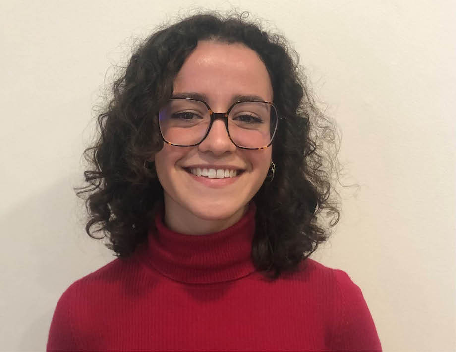 A young woman wearing glasses and a red jumper, smiling